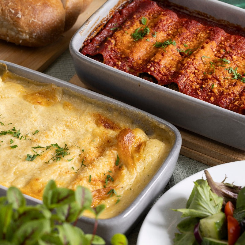 A dish of pumpkin ricotta & sage cannelloni and a dish of spinach & feta cannelloni sit on a table.