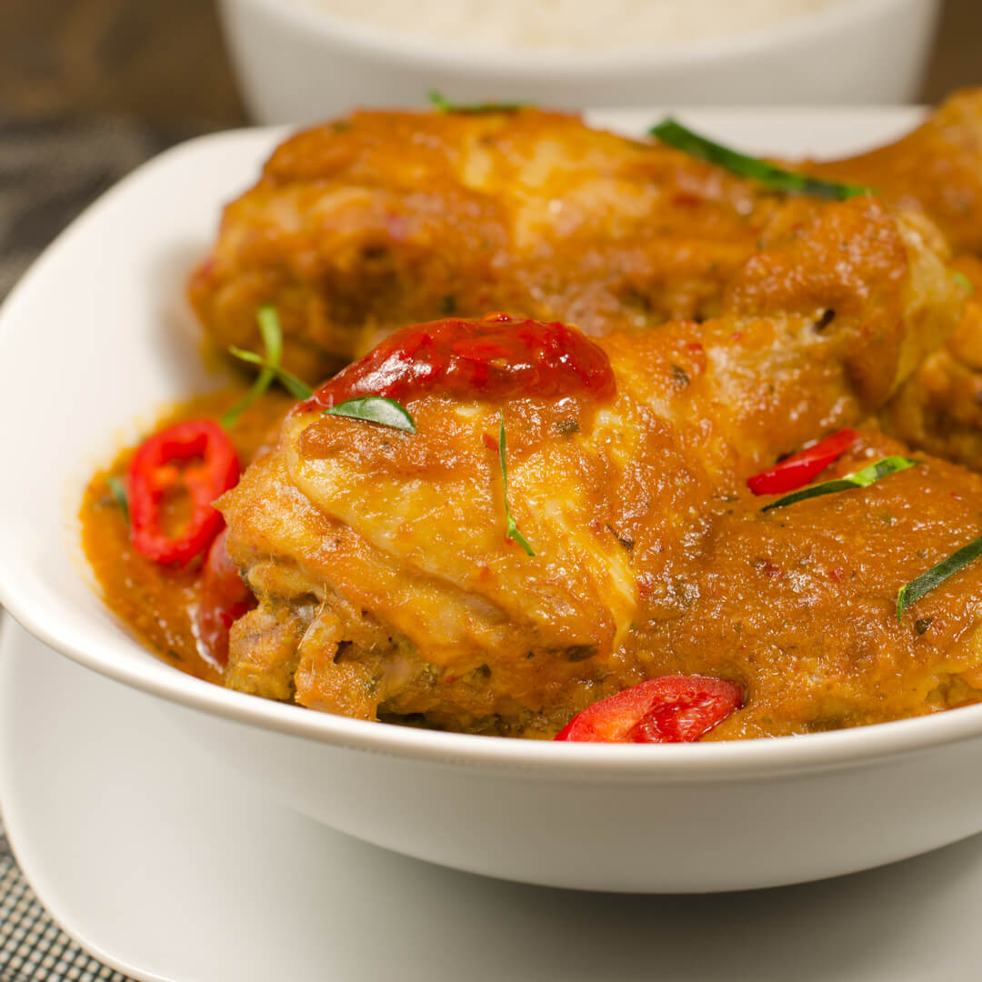 Chicken drumsticks in a satay sauce, garnished with fresh chilli & lime leaves