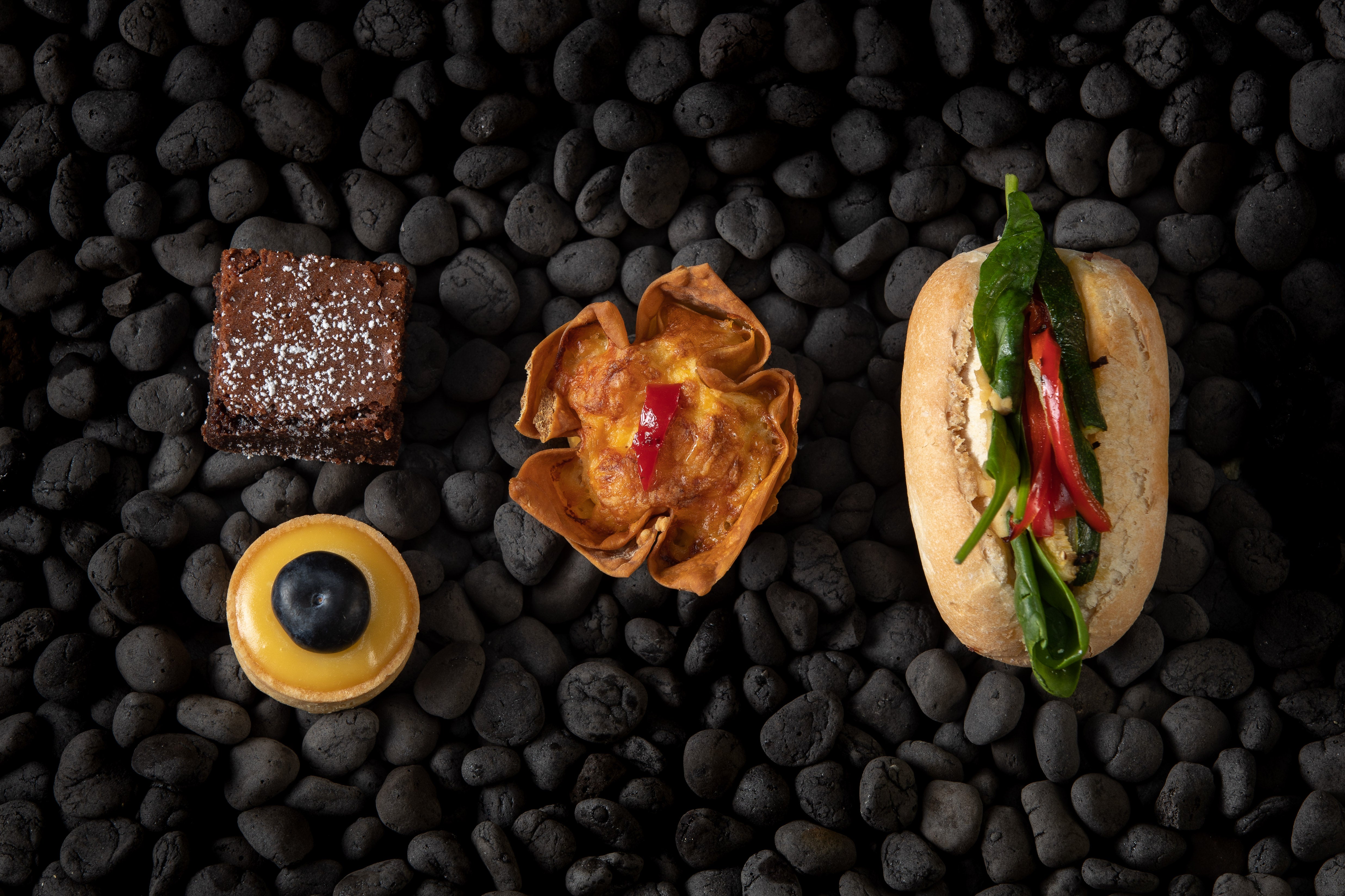 Three small appetizers on black pebbles