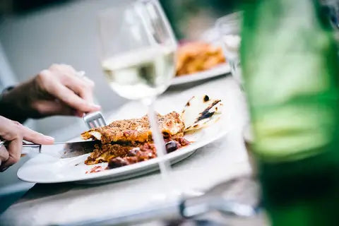 Person cutting into a meal with wine