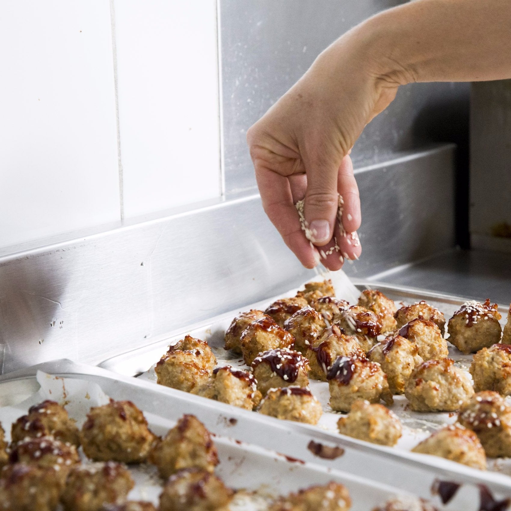ready made home delivery meals featuring Sesame chicken balls being sprinkled with sesame seeds