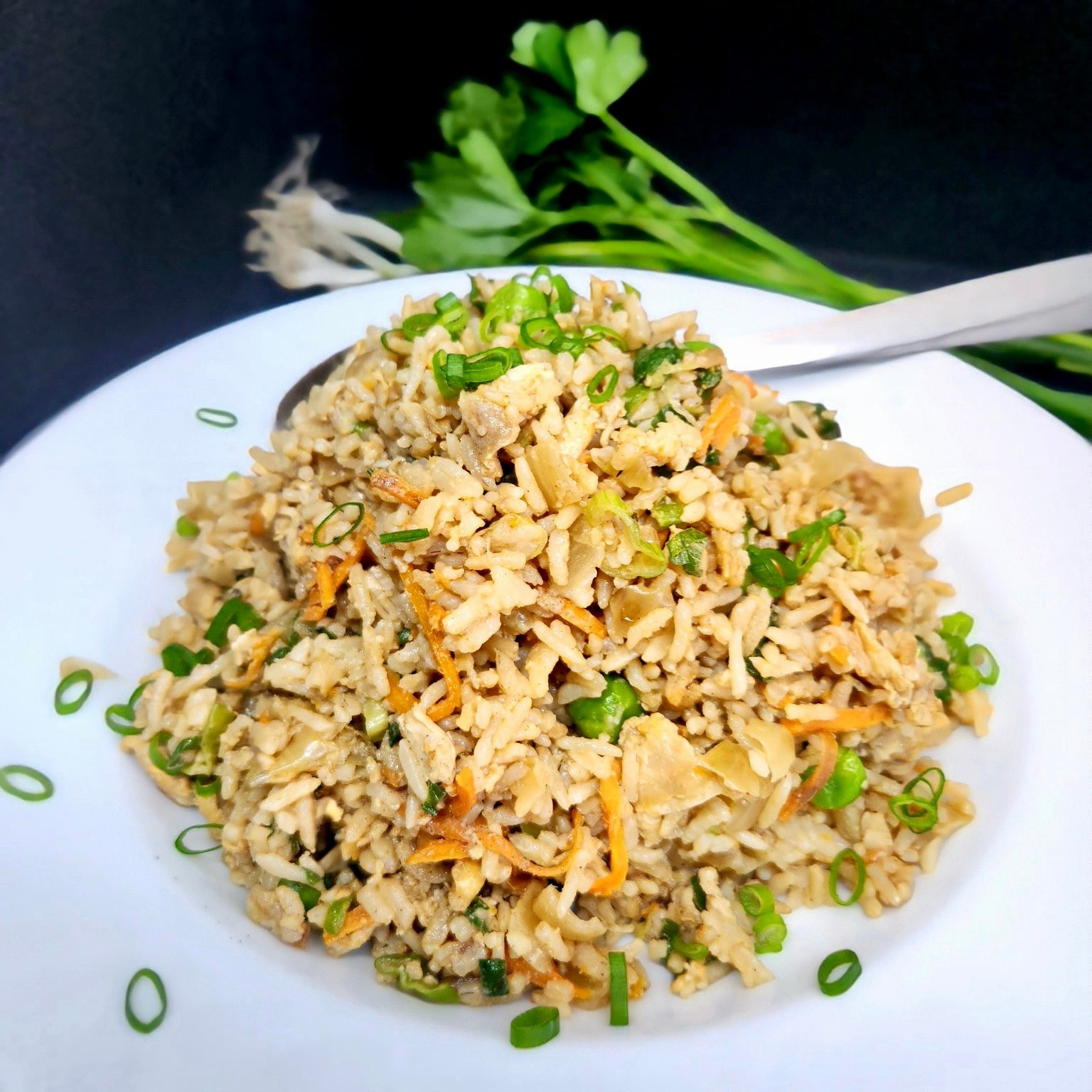 Fried rice sitting in a white bowl on a black background. Melbourne & Sydney meal delivery.